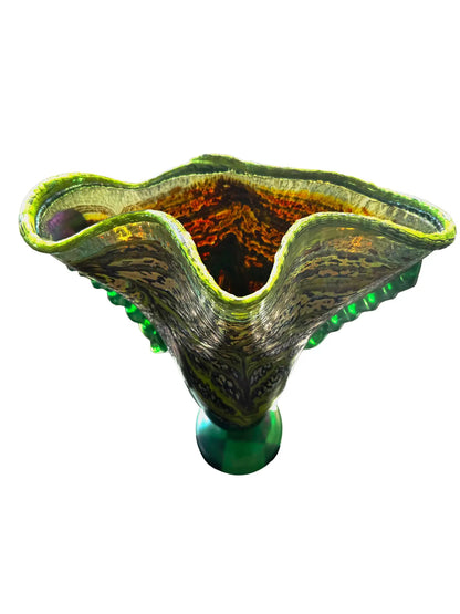 This large, fluted glass vessel, titled 'Hope Springs Eternal,' is a stunning display of color and craftsmanship. It features vivid lime green and deep purple hues, complemented by winter-like tones. The textured surface, ridged sides, and flared silhouette create an elegant flow of color and movement, making it a striking statement piece. Dimensions are approximately 13.75 inches in width and 11.25 inches in height, weighing 4.56 pounds, crafted from glass. Perfect for decorative use.