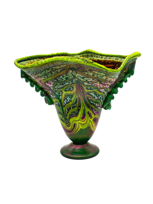 This large, fluted glass vessel, titled 'Hope Springs Eternal,' is a stunning display of color and craftsmanship. It features vivid lime green and deep purple hues, complemented by winter-like tones. The textured surface, ridged sides, and flared silhouette create an elegant flow of color and movement, making it a striking statement piece. Dimensions are approximately 13.75 inches in width and 11.25 inches in height, weighing 4.56 pounds, crafted from glass. Perfect for decorative use.