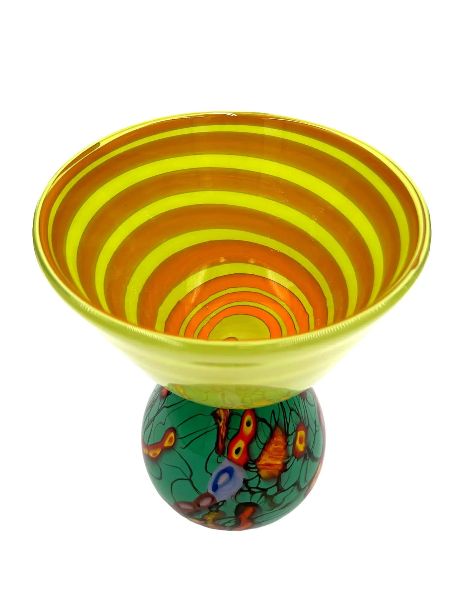 This vibrant glass sculpture, 'Mini Me' by Steve Palmer, showcases a bold abstract design with colorful swirls and organic patterns on a rounded base, contrasted by a translucent lime green top with subtle horizontal stripes. Its playful colors and shapes make it a striking statement piece suitable for contemporary and artistic settings. Dimensions are approximately 7 inches wide, 9 inches high, and 4.5 inches deep, weighing 4.4 pounds, and it is crafted from handblown glass.
