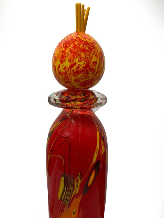 A vivid red glass sculpture titled "Red Inferno" by renowned American artist Steve Palmer features swirling yellow and orange accents, a decorative orb, and flame-colored spikes. Handblown with rich warm hues, it's a striking collector’s piece measuring 30 inches tall and weighing 20.7 lbs.