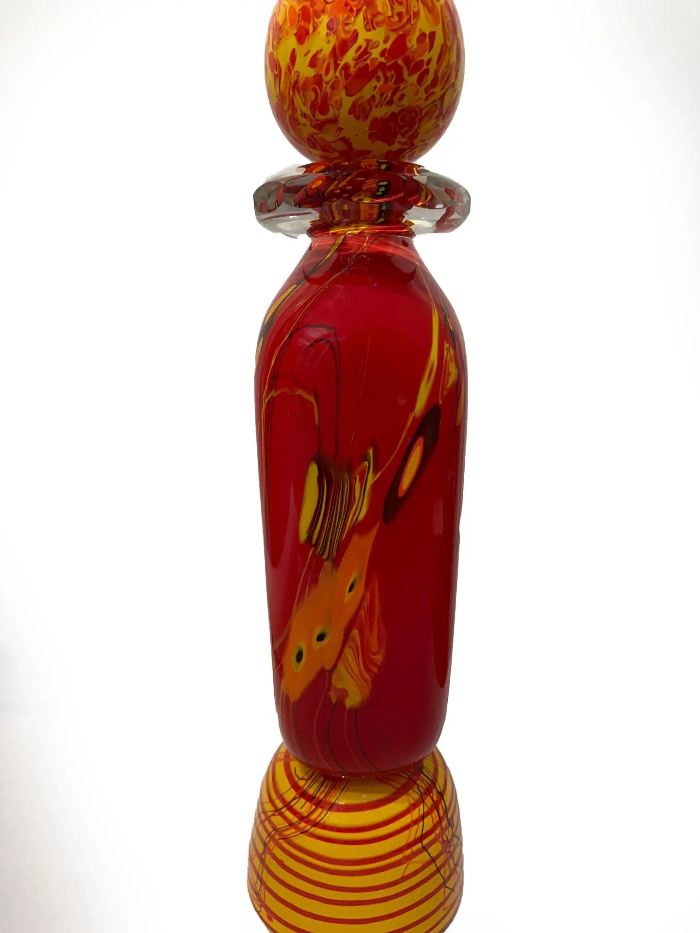 A vivid red glass sculpture titled "Red Inferno" by renowned American artist Steve Palmer features swirling yellow and orange accents, a decorative orb, and flame-colored spikes. Handblown with rich warm hues, it's a striking collector’s piece measuring 30 inches tall and weighing 20.7 lbs.
