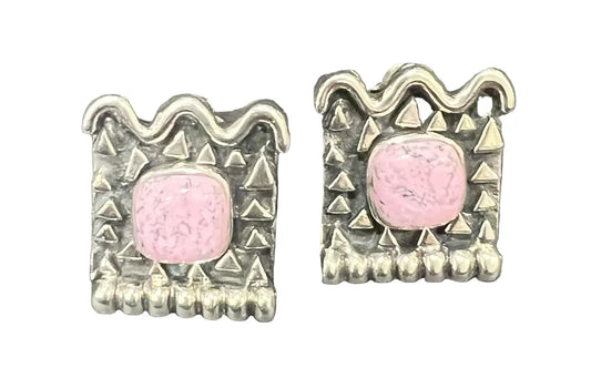 A pair of silver-toned square earrings with a central pink cabochon stone and textured geometric borders.