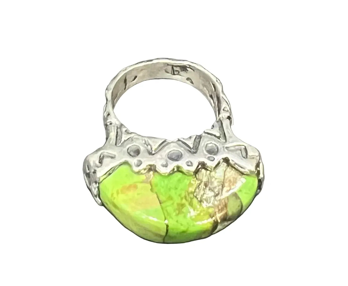 A silver ring featuring a large, organic-shaped green stone with natural matrix cracks. worn on its own, it can also be stacked with other rings for a layered, collected look.